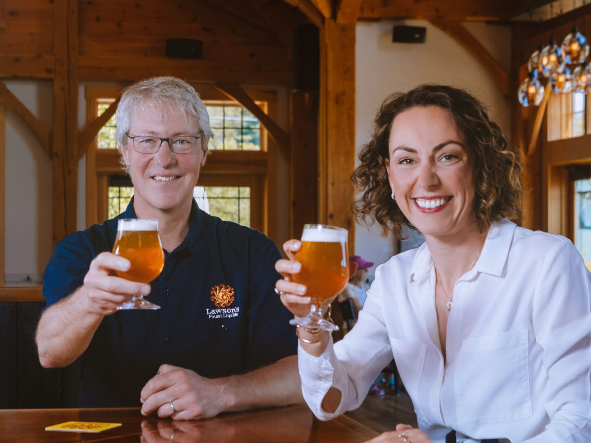 Sean Lawson and Adeline Druart sit at the Lawson's Finest bar and cheers each other with glasses of Sip of Sunshine IPA.